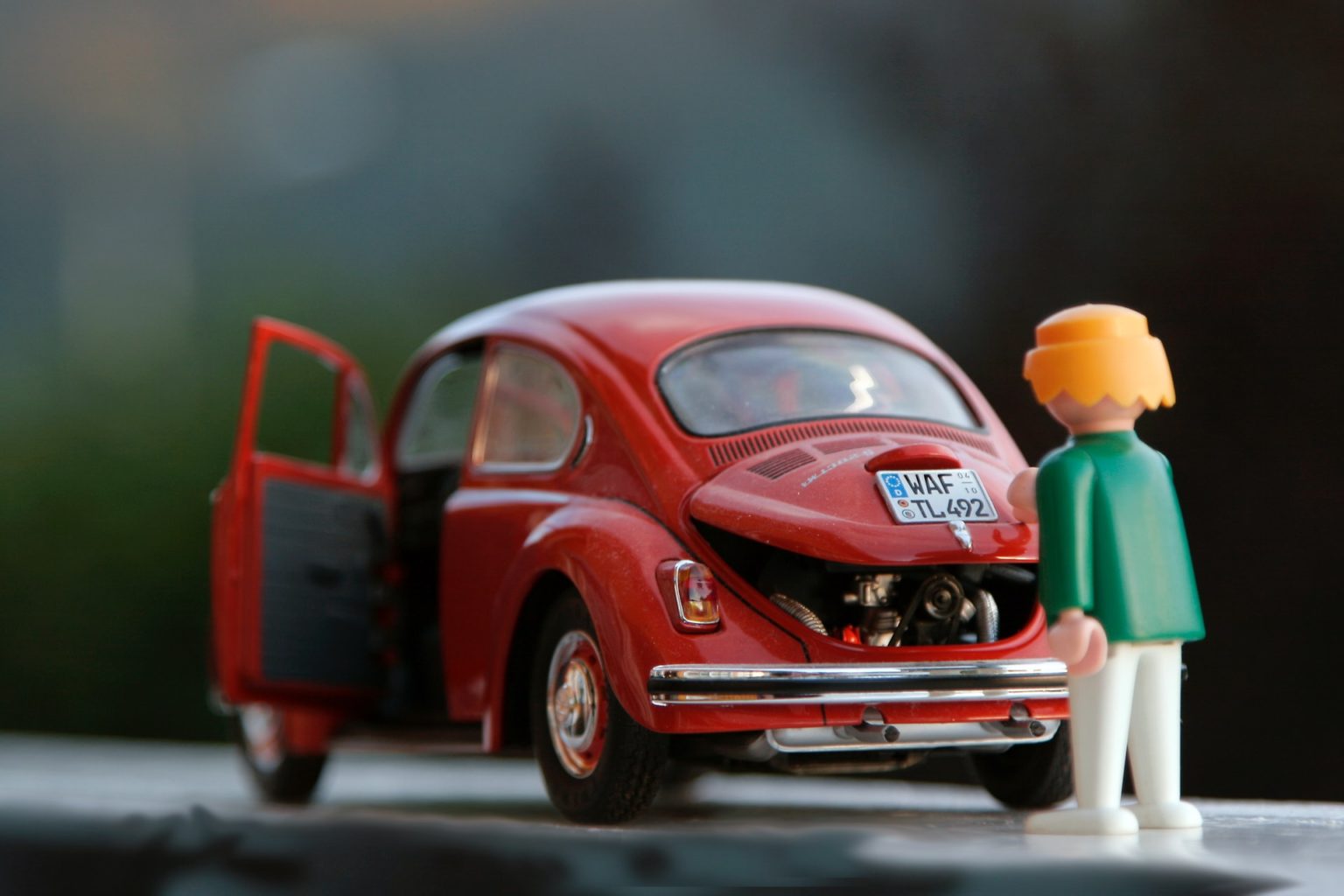 a toy figure next to a red car