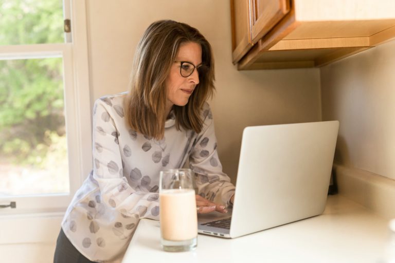 a person sitting at a table with a laptop and a glass of milk