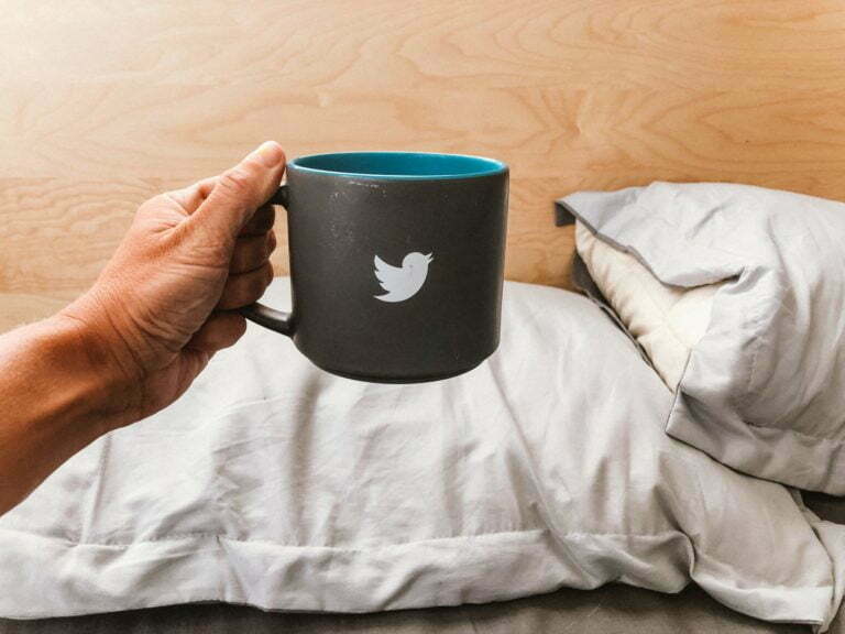 Hand holding mug with a tweeter bird sign