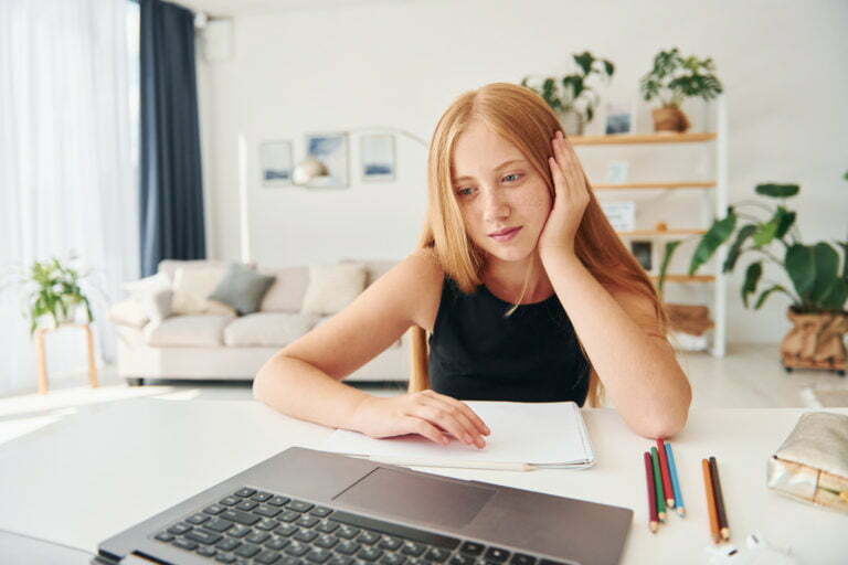 Online school. Female teenager with blonde hair is at home at daytime